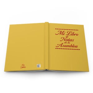 May include: An open notebook with a solid yellow cover. The right side features red text that reads Mi Libro de Notas de la Asamblea, framed by two dashed lines. The bottom left corner displays the text The Lunas and a small square QR code.