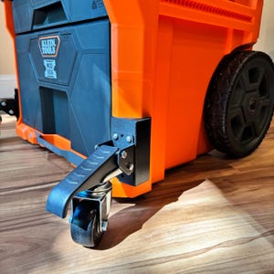 May include: An orange and black Klein Tools Mod Box on wheels. The tool box has a black lid and a black front panel with the Klein Tools logo. The tool box has a handle and a pair of wheels for easy transport.