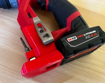 Può includere: Un trapano rosso e nero con una clip in metallo argentato e una batteria nera con la scritta "M12 REDLITHIUM XC4.0".
