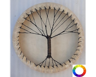 May include: A round, white, leather drum with a black tree-like design in the centre. The drum is held together by a black string lacing.