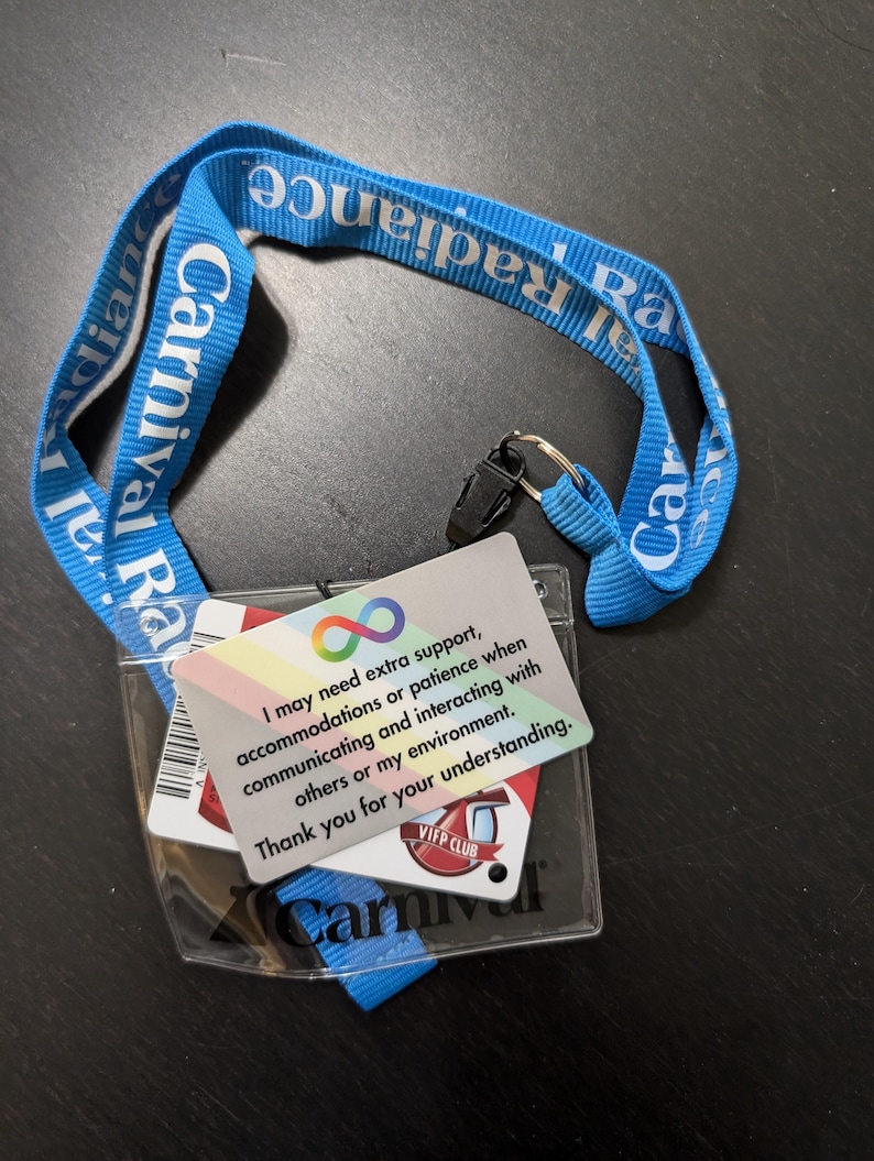 May include: A blue lanyard with the text "Carnival Radiance" printed on it. A clear plastic badge holder with a white card that reads "I may need extra support, accommodations or patience when communicating and interacting with others or my environment. Thank you for your understanding." and a red card with the text "VIP Club Carnival" is attached to the lanyard.