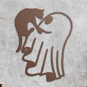 May include: A brown metal wall art piece featuring a continuous line silhouette of a cat perched atop a ghost shape. The design is crafted from a single piece of textured brown metal, forming the outlines of both figures in a connected, fluid form.