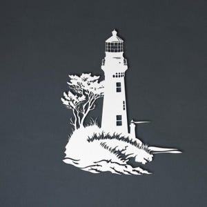 May include: A white silhouette wall art piece depicting a lighthouse standing on a rocky outcrop with a tree and crashing waves at the base. The design features clean cutouts for the lighthouse windows and lantern room against a dark background.