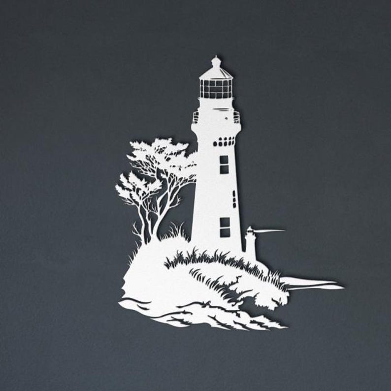 May include: A white silhouette wall art piece depicting a lighthouse standing on a rocky outcrop with a tree and crashing waves at the base. The design features clean cutouts for the lighthouse windows and lantern room against a dark background.