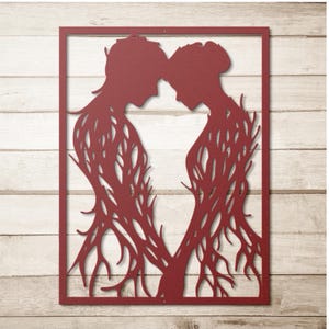 May include: A red metal wall art piece featuring two figures in profile, their heads touching. The figures are connected by a network of branch-like lines, all within a rectangular frame. The artwork is mounted on a light wood background.