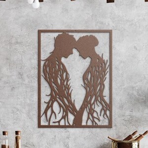 May include: A brown metal wall art piece featuring two figures in profile, their heads touching. The figures are framed within a rectangular border. The bodies are stylized with a tree-like design, creating a unique and artistic representation.