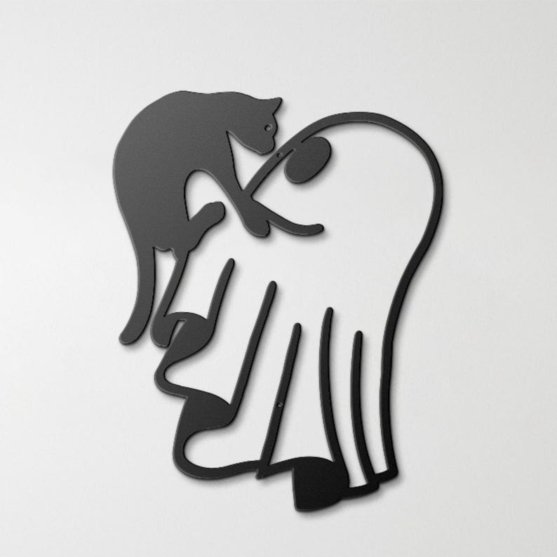 May include: A black metal wall art piece featuring a silhouette of a cat perched on top of a ghost. The design is composed of clean, continuous lines forming the shapes of the feline and the draped figure, creating a flat, minimalist aesthetic.
