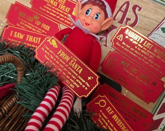 May include: A plush elf doll with a red suit and hat, white collar, and red-and-white striped legs, positioned on a wooden board with printed Christmas-themed tickets. The tickets include text such as Santa Claus Express, From Santa, Naughty List Warning, and Gold Star Voucher.