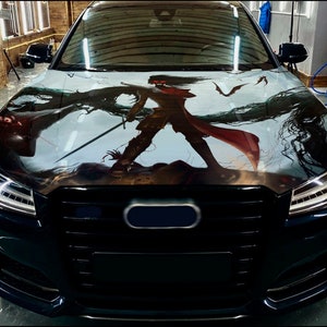 May include: A black car with a custom anime-style wrap featuring a character with red hair and a red cape. The wrap covers the hood of the car and features a dark background with a light blue sky.
