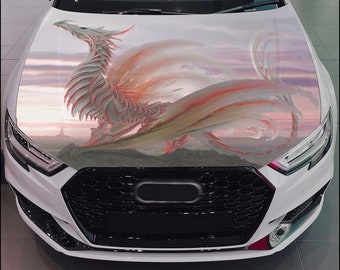 May include: A white car with a black grill and a dragon graphic on the hood. The dragon is pink and white with a sunset background.