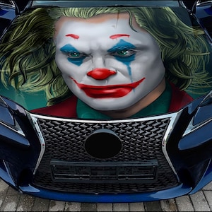 May include: A blue car with a Joker face graphic on the hood. The graphic is a close-up of the Joker's face with green hair, white makeup, and a red smile.