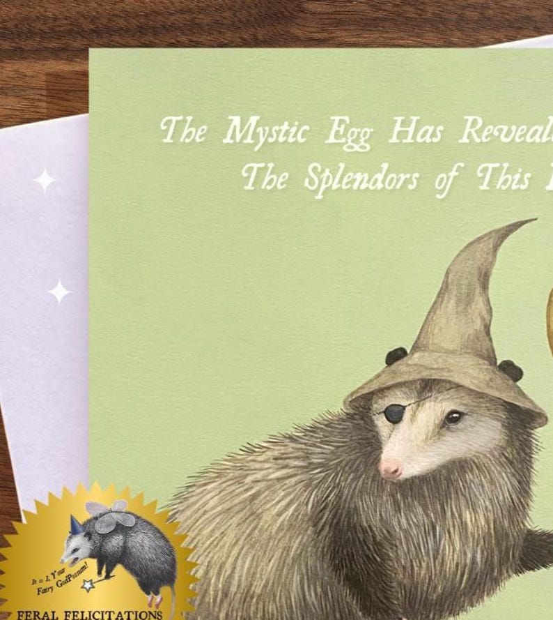 Może przedstawiać: Kapryśna kartka z życzeniami z opossem w kapeluszu czarodzieja i przepaską na oku. Na karcie widnieje napis "The Mystic Egg Has Revealed The Splendors of This". Złota pieczęć z kresk&oacute;wkowym opossem znajduje się w lewym dolnym rogu.