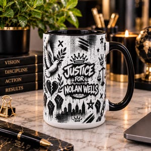 Puede incluir: Una taza de cerámica blanca con asa e interior negros, que presenta ilustraciones gráficas en negro que incluyen una paloma, un corazón roto, una corona, una balanza de justicia, puños en alto y un horizonte urbano, con el texto Justice For Nolan Wells.