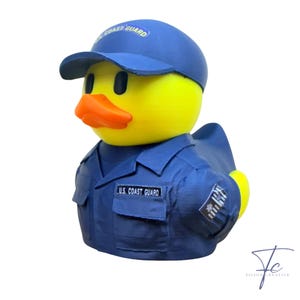 May include: A yellow rubber ducky wearing a blue Coast Guard uniform and cap. The cap has "Coast Guard" printed on it. The uniform has a patch that says "U.S. Coast Guard". The duck has an orange beak and black eyes.