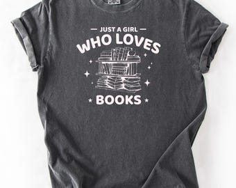 May include: A dark gray t-shirt with the text "Just a girl who loves books" printed in white. A graphic of a bookshelf with books stacked on it is printed below the text.