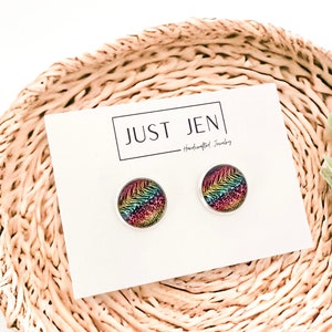 May include: A pair of rainbow and animal print stud earrings on a white card with the text "JUST JEN - Handcrafted Jewelry".