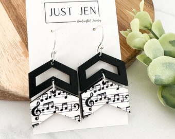 May include: Black and white chevron earrings with a music note pattern. The earrings are on a white card with the text "JUST JEN - Handcrafted Jewelry".