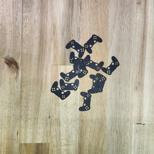 以下が含まれることがあります： 薄い茶色の木製の表面に、星形に配置された黒いプラスチック製のビデオゲームコントローラーの切り抜きがいくつかあります。