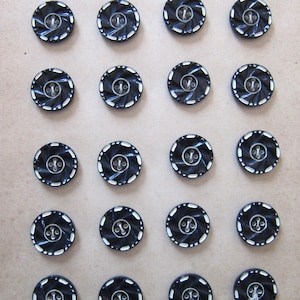Könnte beinhalten: Eine Sammlung von 18 schwarzen und weißen Knöpfen mit einem Wirbelmuster. Die Knöpfe haben einen weißen Rand und eine weiße Mitte mit einem kleinen schwarzen Kreis in der Mitte.