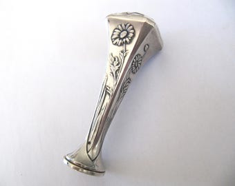 May include: Silver seal with a floral design. The seal is shaped like a flower with a stem and leaves. The seal is made of silver and has a polished finish.