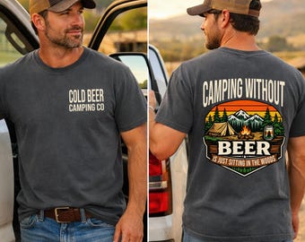 May include: A charcoal gray t-shirt featuring the text COLD BEER CAMPING CO on the front chest. The back displays a graphic of a tent, campfire, and mountains with the text CAMPING WITHOUT BEER IS JUST SITTING IN THE WOODS.