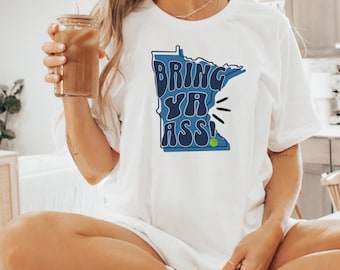 May include: White t-shirt with a blue outline of the state of Minnesota and the text "Bring Ya Ass!" in a retro font. A green and white baseball is in the outline of the state.