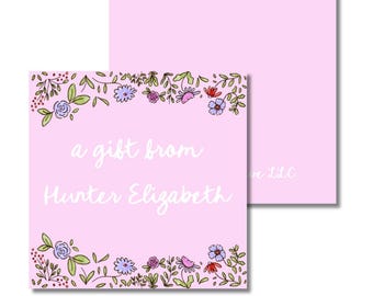May include: A pink gift tag with floral border and the text "a gift from Hunter Elizabeth" in white script. The tag is square with a matching blank tag behind it. The floral border includes blue, purple, and red flowers with green leaves.