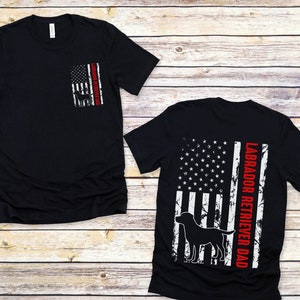 May include: Black t-shirt with a distressed American flag design and the text "Labrador Retriever Dad" in red.