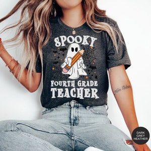 May include: A dark grey heather t-shirt with a spooky ghost holding a pencil and the text "Spooky Fourth Grade Teacher".
