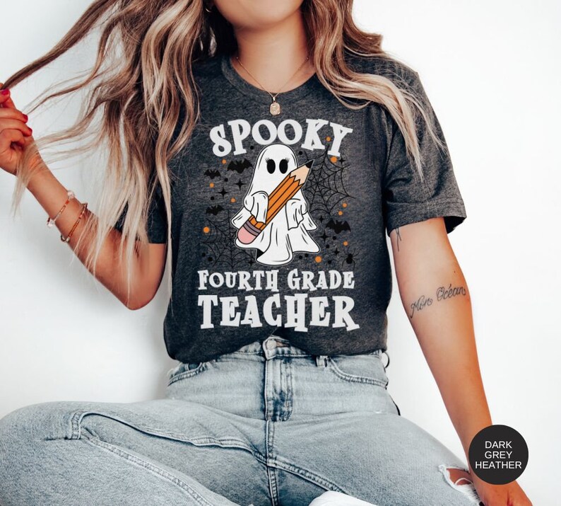 May include: A dark grey heather t-shirt with a spooky ghost holding a pencil and the text "Spooky Fourth Grade Teacher".