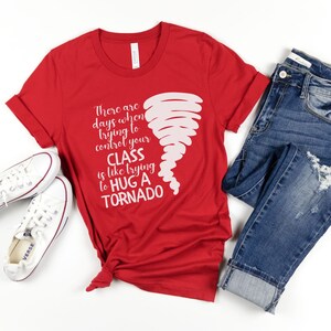 May include: Red t-shirt with a white graphic of a tornado and the text "There are days when trying to control your CLASS is like trying to HUG A TORNADO".
