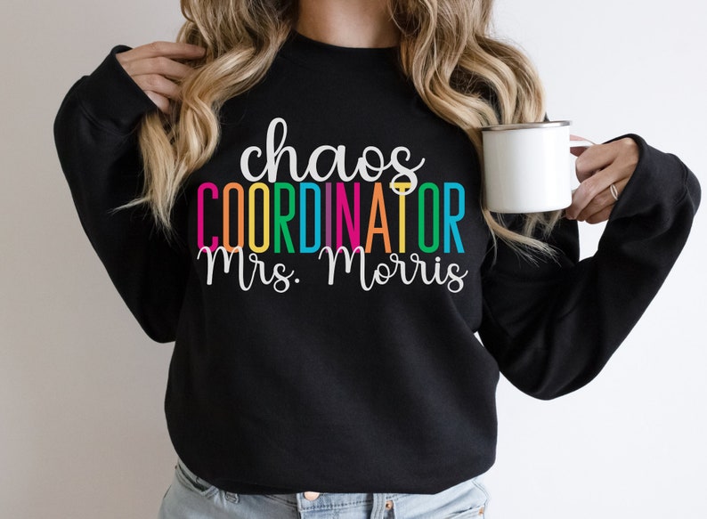 Pu&ograve; includere: Felpa nera con il testo "chaos coordinator Mrs. Morris" in colori arcobaleno.