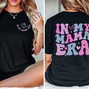 May include: Black t-shirt with a pink and blue graphic that says "In My Mama Era" with butterflies and hearts.