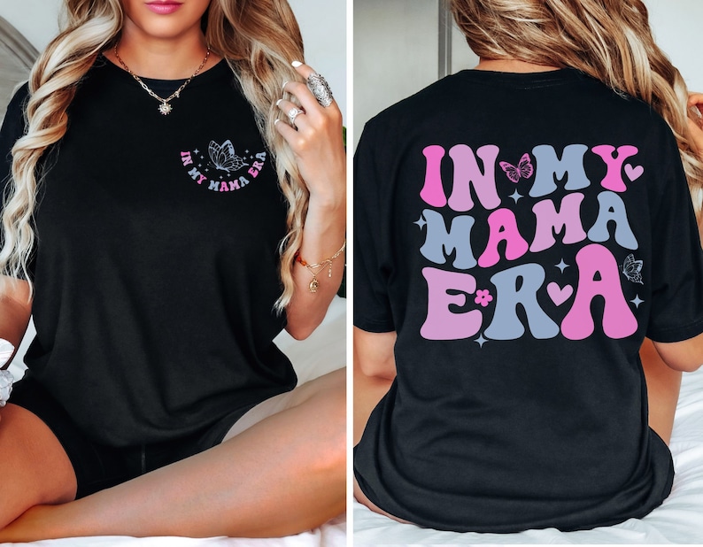 May include: Black t-shirt with a pink and blue graphic that says "In My Mama Era" with butterflies and hearts.