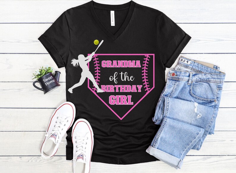 Może przedstawiać: Czarny t-shirt z dekoltem w kształcie litery V z grafiką r&oacute;żowego diamentu baseballowego. Grafika przedstawia białą sylwetkę gracza w softbol, piłkę baseballową i tekst "Grandma of the Birthday Girl".