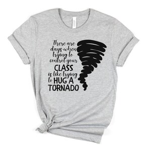 May include: Gray t-shirt with a black graphic of a tornado and the text "There are days when trying to control your CLASS is like trying to HUG A TORNADO".