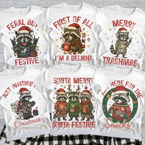 May include: White t-shirts with Christmas-themed raccoon graphics. Designs include raccoons in Santa hats with text like "Feral But Festive," "First of All I'm a Delight," and "Merry Trashmas." Other shirts say "Just Waiting Christmas," "Sorta Merry Sorta Festive," and "Here for the Snacks."
