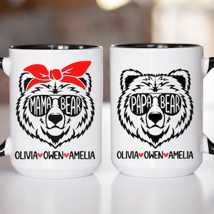 Op de afbeelding: Twee witte keramische mokken met zwarte randen. De mok links heeft een zwart-witte illustratie van een beer met een zonnebril en een rode bandana met de tekst "Mama Bear" en de namen "Olivia Owen Amelia" eronder. De mok rechts heeft een zwart-witte illustratie van een beer met een zonnebril met de tekst "Papa Bear" en de namen "Olivia Owen Amelia" eronder.