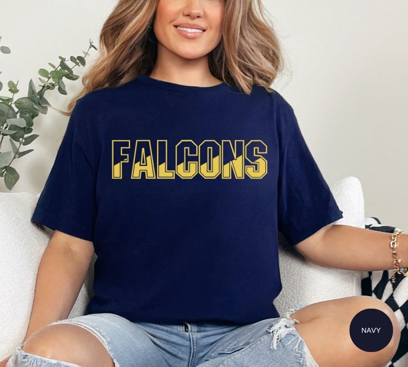 May include: A navy blue t-shirt with the word "FALCONS" printed in yellow on the front.