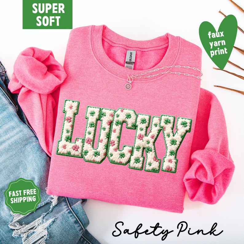 Pu&ograve; includere: Una felpa rosa con la scritta "LUCKY" ricamata in un motivo floreale verde e bianco. La felpa ha un girocollo e maniche lunghe. Il testo "Safety Pink" &egrave; scritto in corsivo in basso.