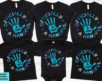 May include: Black t-shirts and a onesie with a blue and white graphic that says "Officially 5 Crew A Handful". The design features a handprint with the number 5 inside. Some shirts have the name "Oliver".
