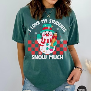 May include: A teal blue t-shirt with a snowman holding a pencil and the text "I love my students snow much".