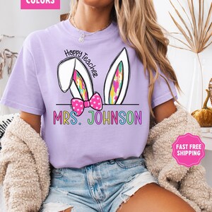 May include: Purple t-shirt with a white bunny ear design and the text "Hoppy Teacher" and "MRS. JOHNSON" in rainbow colors.