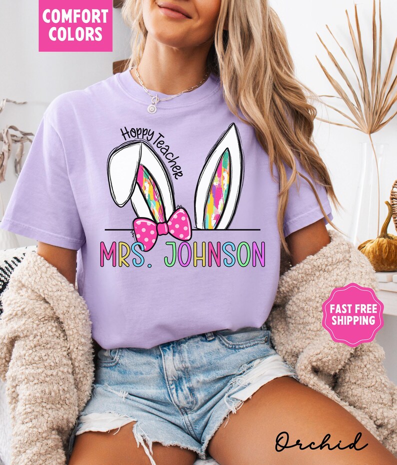May include: Purple t-shirt with a white bunny ear design and the text "Hoppy Teacher" and "MRS. JOHNSON" in rainbow colors.