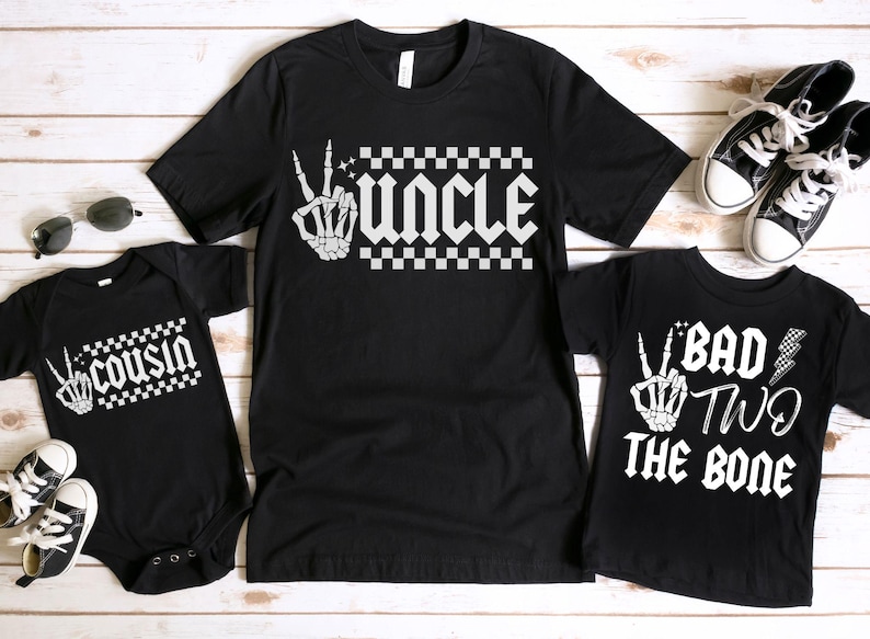 May include: Three black t-shirts with white text and graphics. The shirts say "Uncle", "Cousin", and "Bad Two The Bone".