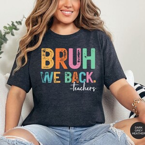 May include: Dark grey heather t-shirt with the text "BRUH WE BACK. -teachers" in rainbow colors.