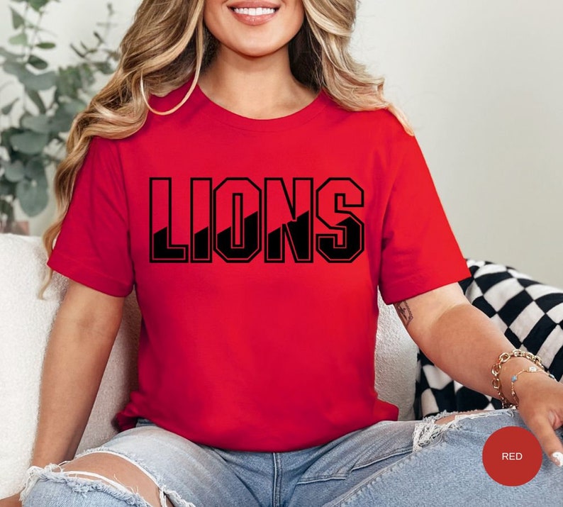May include: A red t-shirt with the word "LIONS" printed in black block letters. The letters have a diagonal black stripe through them.