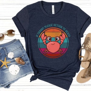 May include: A navy blue t-shirt with a retro-style graphic of a crab with the text "If Crabby Please Return to Beach".
