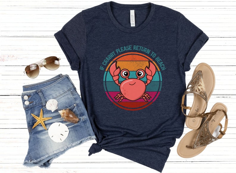 May include: A navy blue t-shirt with a retro-style graphic of a crab with the text "If Crabby Please Return to Beach".