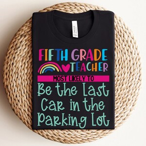 K&ouml;nnte beinhalten: Schwarzes T-Shirt mit einem Regenbogen- und Herzdesign. Der Text lautet "Fifth Grade Teacher Most Likely To Be The Last Car In The Parking Lot".
